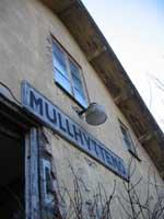 Mullhyttemo stationshus med två namnskyltar den 11 november 2004. - klicka för att förstora