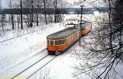 Elmotorvagnar passerar under bron vid Östertysslinge hållplats den 16 februari 1985. - klicka för att förstora Elmotorvagnar passerar under bron vid Östertysslinge hållplats den 16 februari 1985. - klicka för att förstora